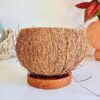 Bougie artisanale dans une véritable noix de coco brute sur socle en bois de cocotier